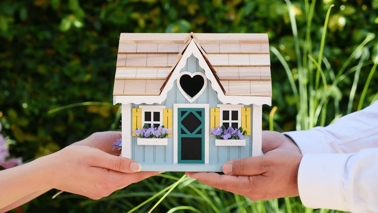 small plastic house in the hands of a young couple