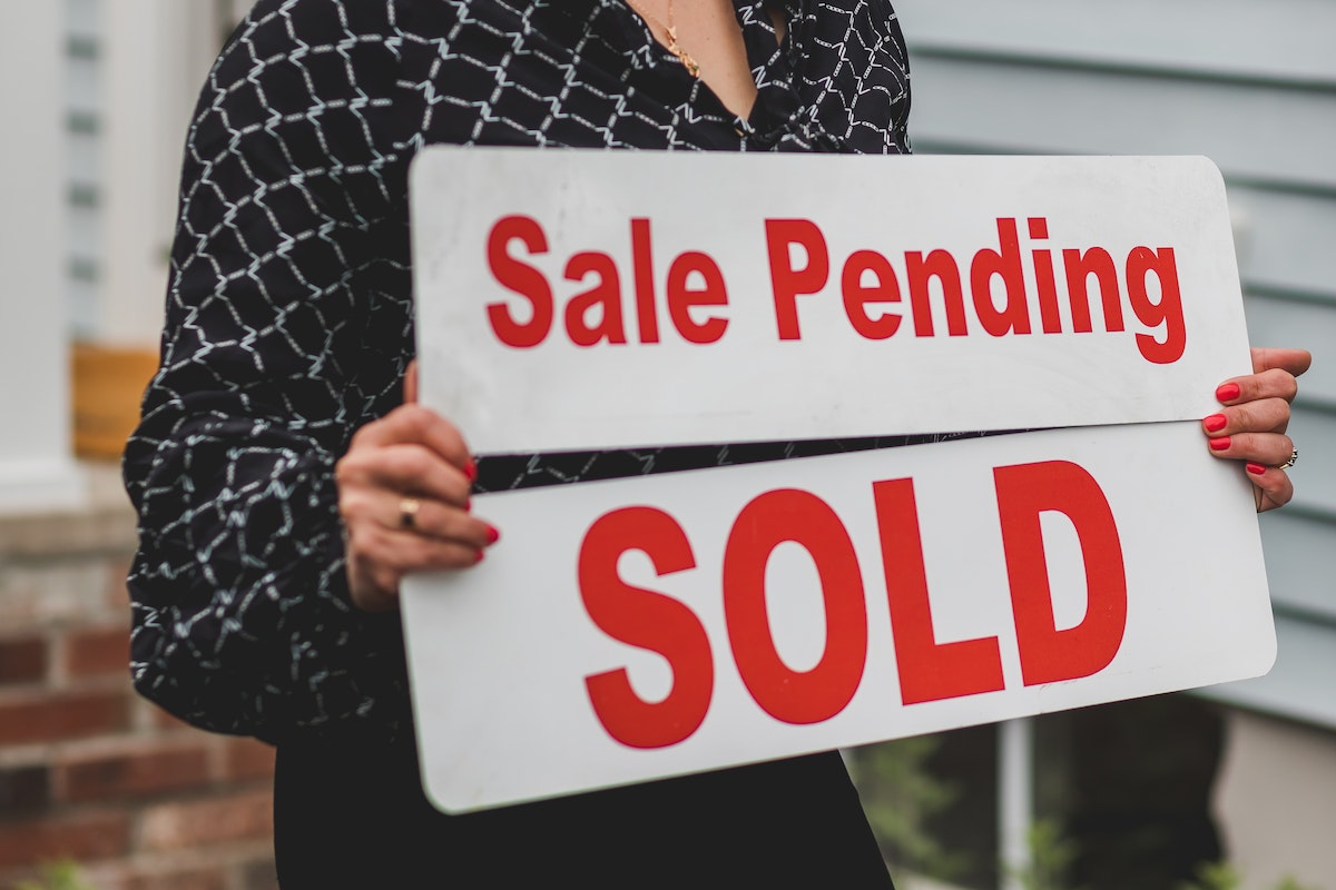 Real estate agent switching signage on an already sold home